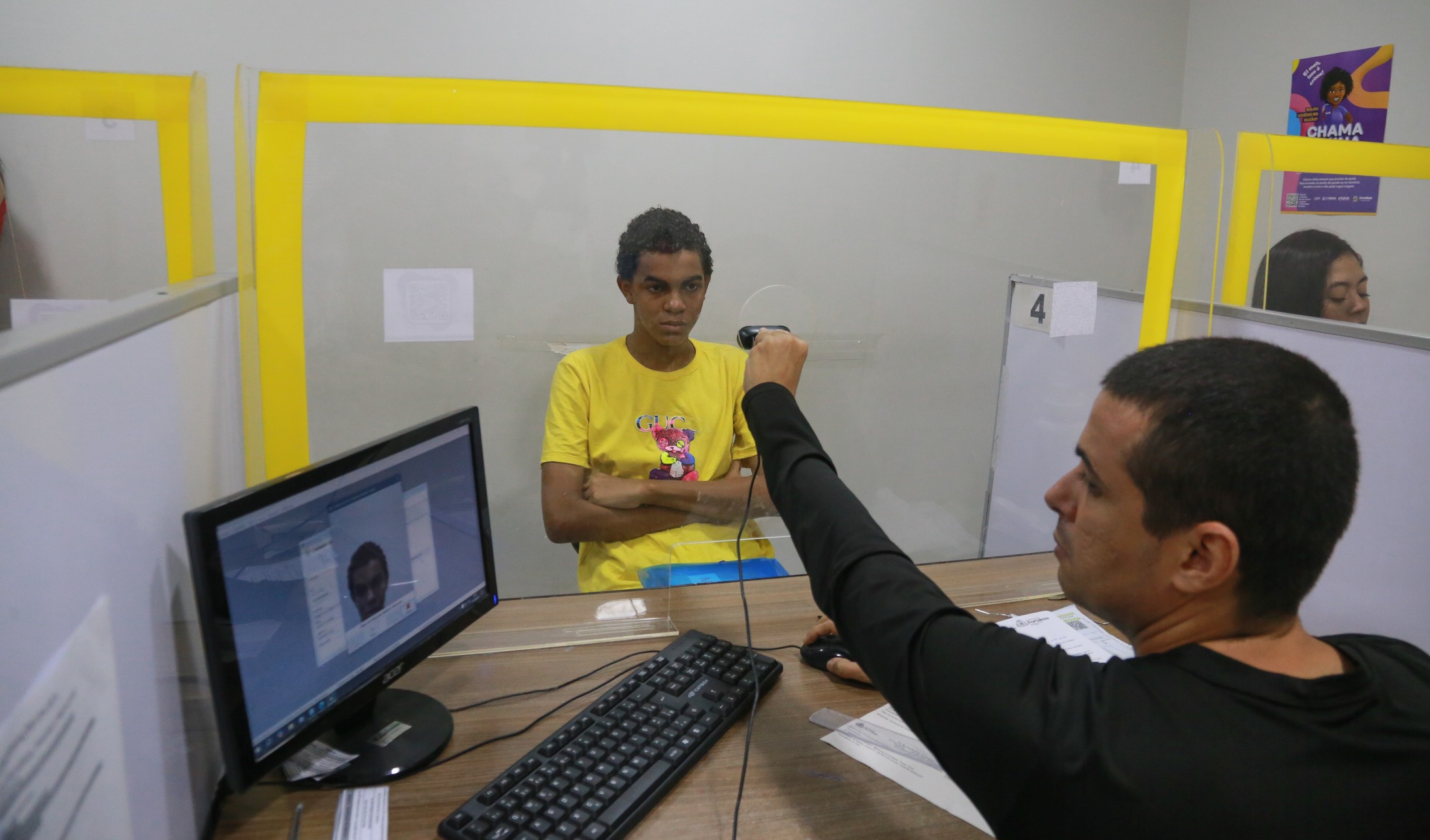 funcionário da Etufor tira foto digital de um estudante num guichê de atendimento da Etufor